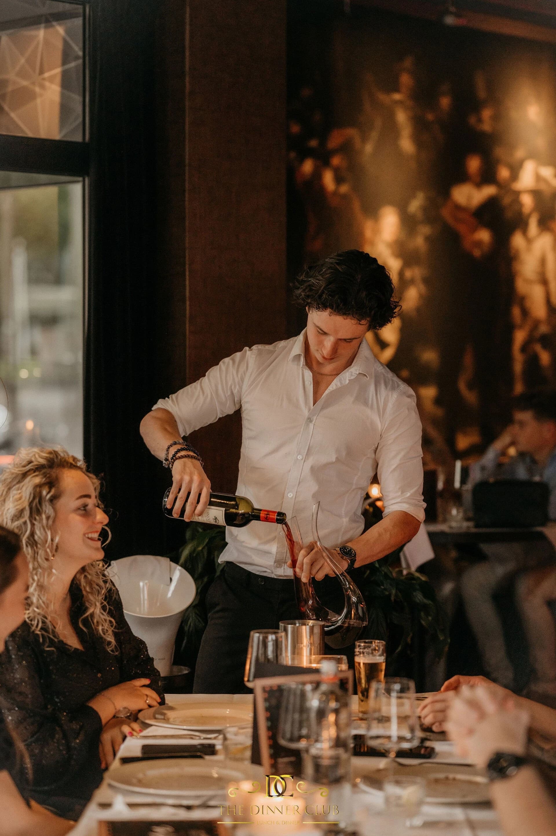 Wijn wordt aan tafel ingeschonken bij The Dinnerclub